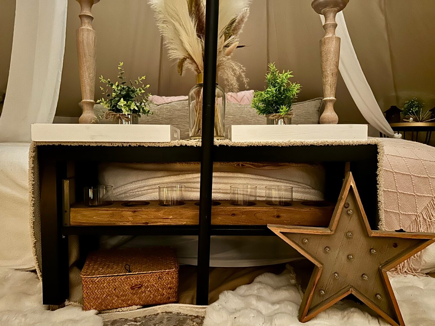 Detalle bajo la cama: estrella de madera marquesina, canasta, velas y pampas.